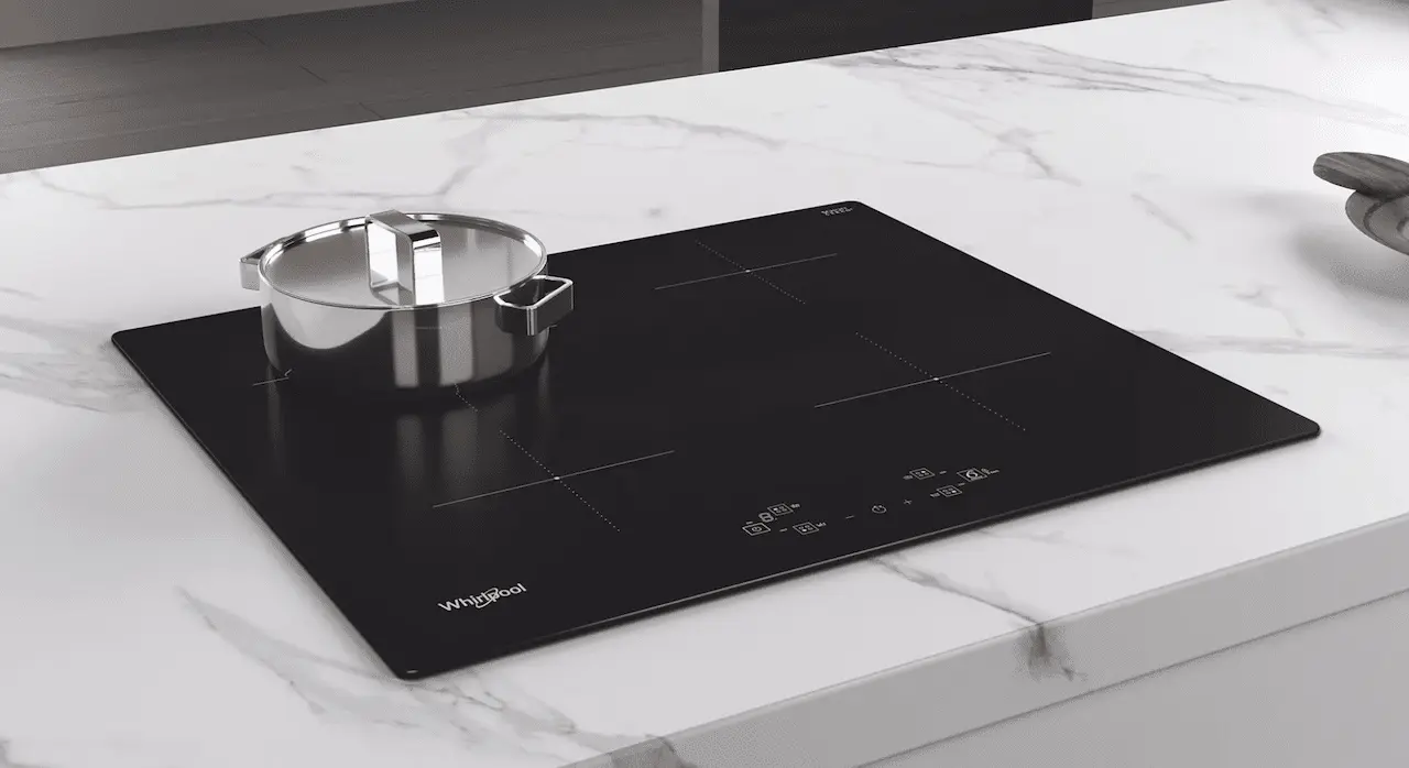 Une plaque de cuisson à induction Whirlpool intégré à un plan de travail en marbre blanc.