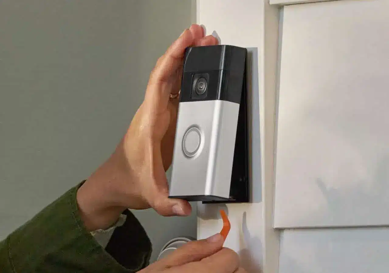 Gros plan sur les mains d'un bricoleur installant une sonnette sans fil.