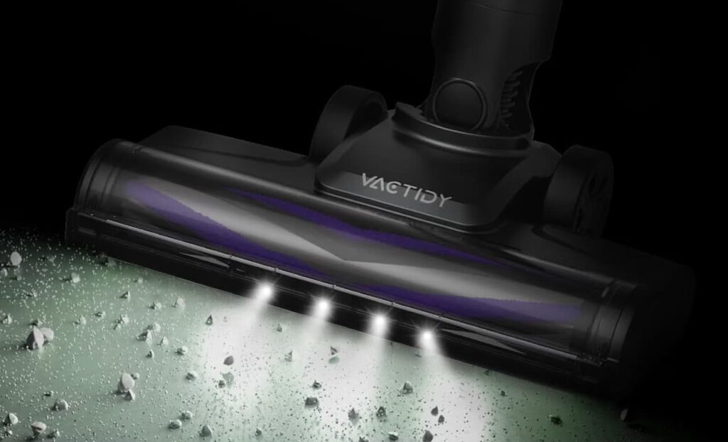 Zoom sur un aspirateur balai sans fil de la marque Vactidy, qui aspire la poussière sur un sol dur.
