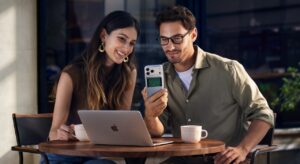 Un homme et une femme prenne un café en travaillant sur leur macbook. L'homme tient un iphone qui se recharge avec le batterie magnétique Ugreen MagFlow Pro 25W 10000 mAh Qi2