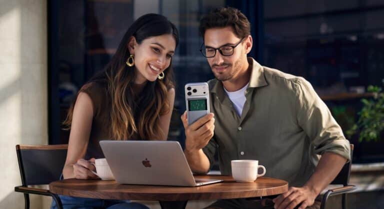 Un homme et une femme prenne un café en travaillant sur leur macbook. L'homme tient un iphone qui se recharge avec le batterie magnétique Ugreen MagFlow Pro 25W 10000 mAh Qi2