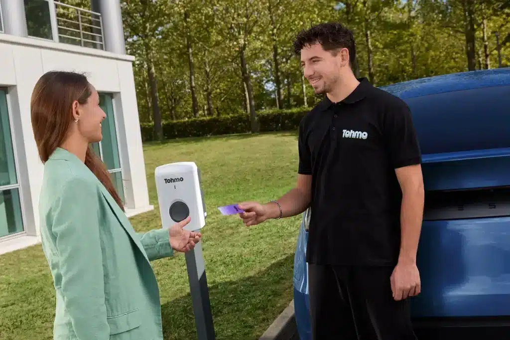 Un installateur Tohmo et sa cliente devant une borne de recharge VE Tohmo.