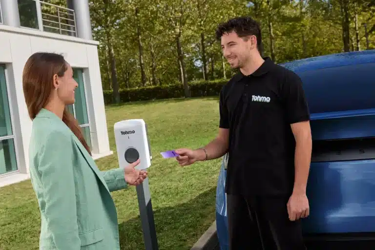 Un installateur Tohmo et sa cliente devant une borne de recharge VE Tohmo.