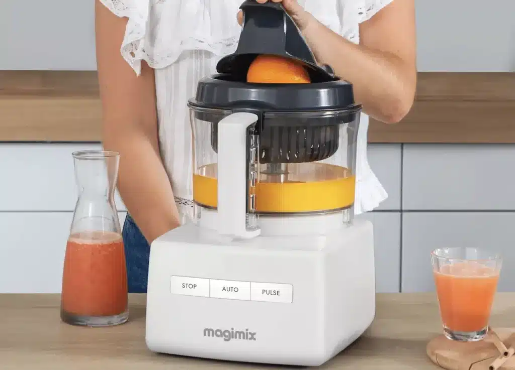 Une femme prépare un jus de fruits à l'aide d'un robot multifonctions.