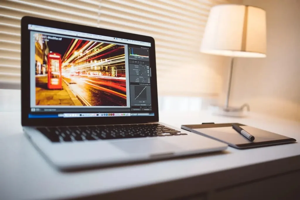 Un ordinateur portable posé sur un bureau avec un logiciel de montage vidéo visible sur l'écran.