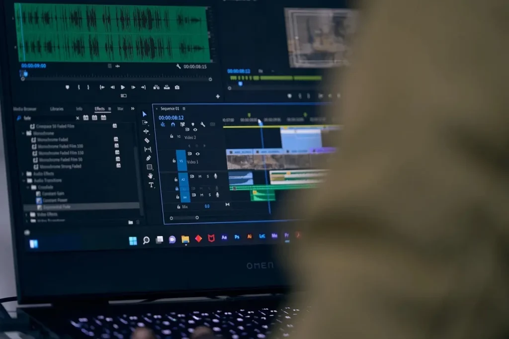 Une personne de dos entrain de faire du montage vidéo sur un PC portable.
