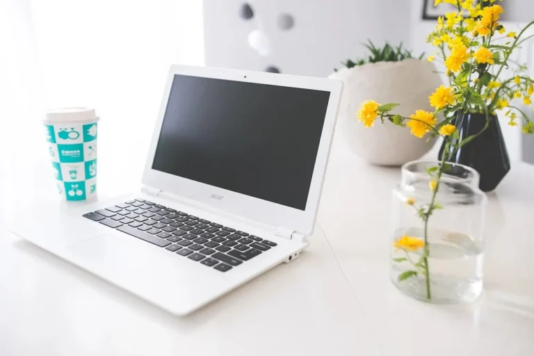 Un ordinateur portable blanc posé sur un bureau blanc.