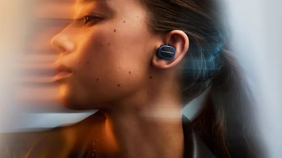 Une jeune femme qui porte des écouteurs sans fil de la marque Bowers & Wilkins