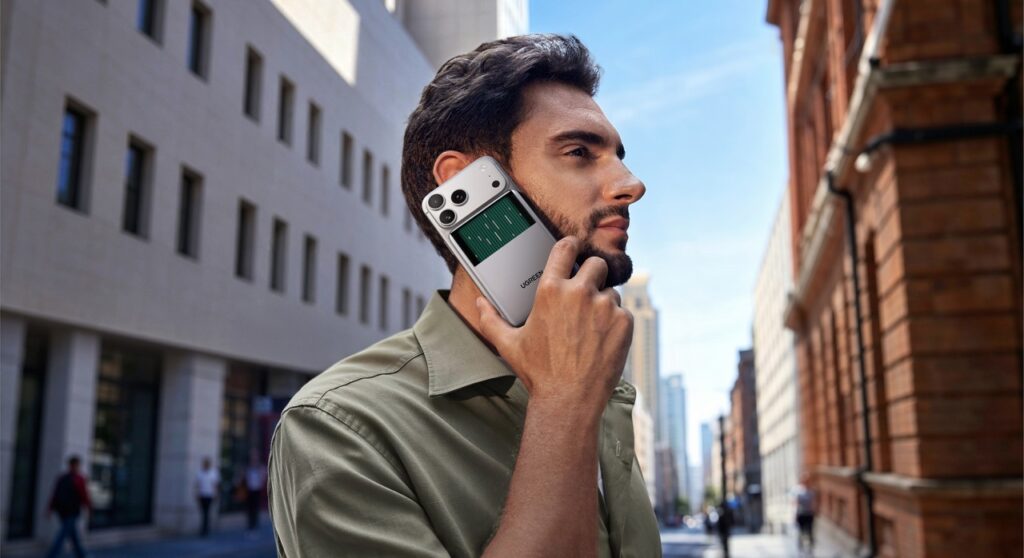 Un homme tient dans sa main un iphone avec la batterie magnétique Ugreen MagFlow Pro Qi2 25W 10000 mAh.